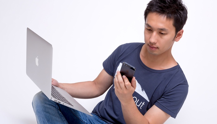 パソコンとスマートフォンを見る男性
